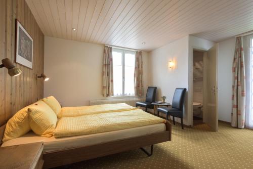 a bedroom with a bed and two chairs in it at Hotel Bel-Air Eden in Grindelwald