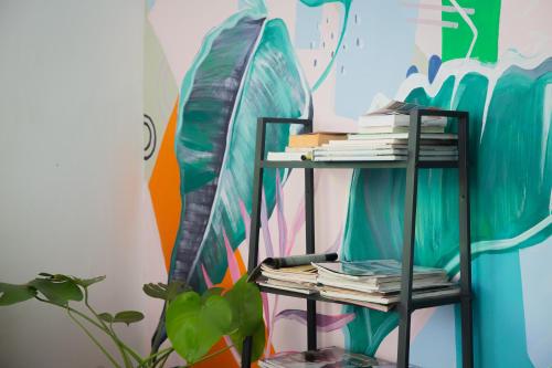 a shelf with books on it next to a surfboard at Sleep Here Hostel, Melaka in Melaka