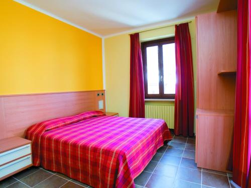 a bedroom with a bed and a window with red curtains at Residenza Gildo in Frabosa Soprana