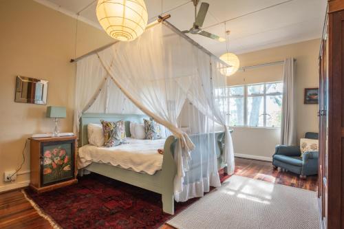 1 dormitorio con cama con dosel y silla azul en Tygerfontein Safari Villa, en Reserva de Amakhala