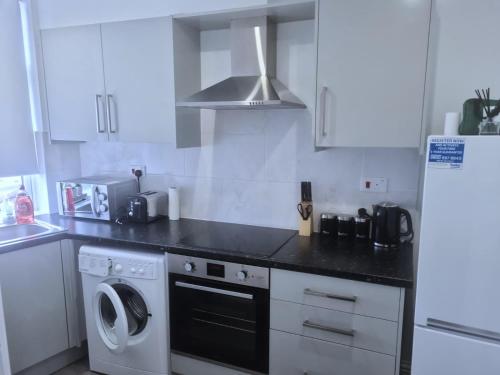 a kitchen with white cabinets and a washer and dryer at Attractive 2 bed apartments free Wi-Fi and parking in Croydon