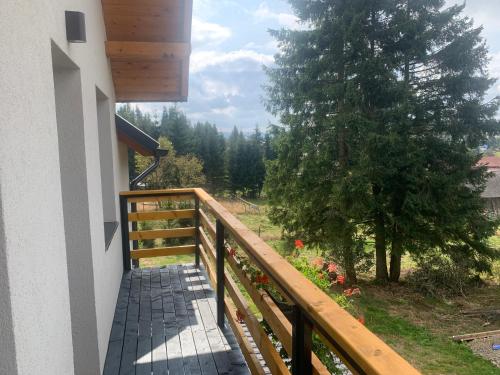 a balcony with a wooden railing and a tree at Pensiunea Denisa & Madalina in Beliş