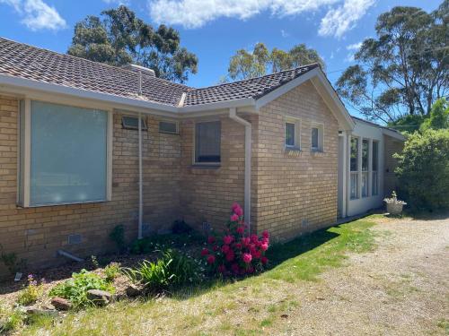 a small brick house with pink flowers in the yard at The Delightful Tee House - Kilmore in Kilmore