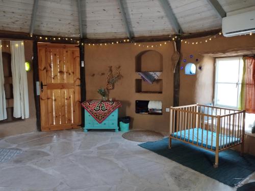 um quarto com um berço no canto de um quarto em ביתהבוצ - מקום טבעי למפגשים em Talmei Yosef