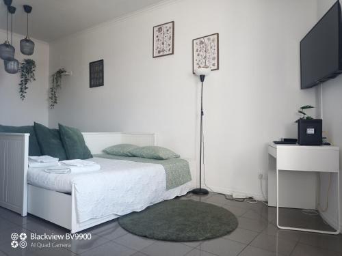 a white bedroom with a bed and a tv at Oporto apartment Batalha in Porto