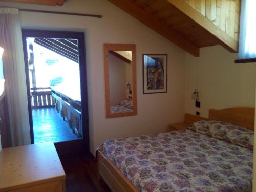a bedroom with a bed and a door to a balcony at B&B Casa Bazzanella in Cavalese