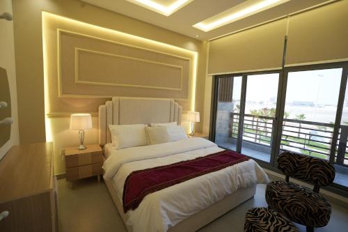 a bedroom with a large bed and a large window at منتجع اجمكان Ajmkan Resort in Al Khobar