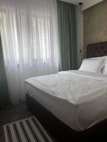 a bedroom with a bed with white sheets and windows at Vlasinsko jezero VILA BEST in Surdulica