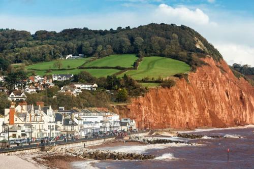 a group of houses on a cliff next to the ocean at Delightful Devon Cottage in East Budleigh