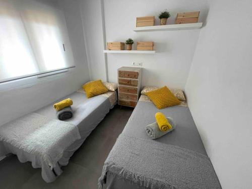 una camera con tre letti con cuscini gialli e una finestra di Estudio Primera línea de Playa a Tavernes de Valldigna