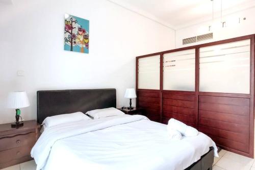 um quarto com uma cama grande e lençóis brancos em StoneTree - Furnished Studio with Lake View and near Metro em Dubai