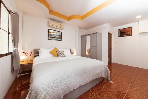a bedroom with a white bed with a yellow ceiling at Garden Home 4 in Haad Yao