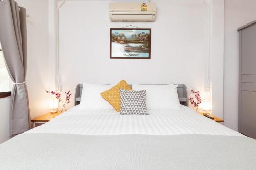 1 dormitorio con 1 cama blanca con sábanas y almohadas blancas en Garden Home 4, en Haad Yao