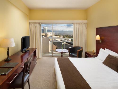 a hotel room with a bed and a desk and a window at Hotel des Mille Collines in Kigali