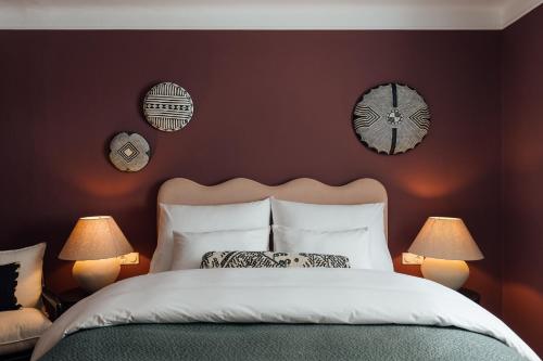 a bedroom with a bed with two lamps and two clocks at Clemonte Hotel - Your Reception-less Boutique Hideaway in Salzburg