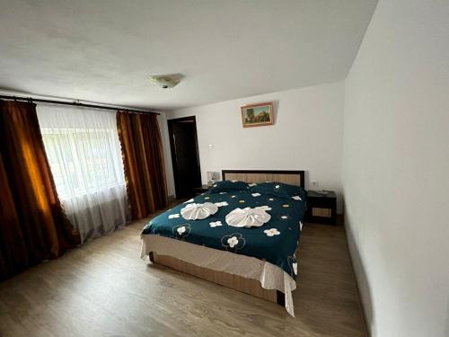 Un dormitorio con una cama con una manta verde con flores en Casa Andra, en Baia de Fier