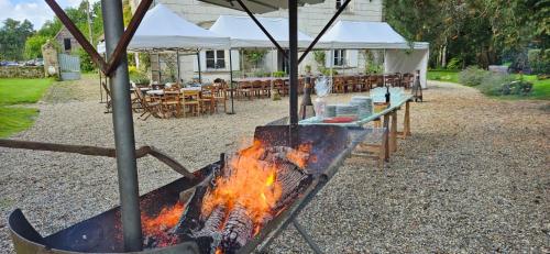 a fire in a grill in a yard with tables and chairs at Petit manoir de la berthenlaire in Baincthun