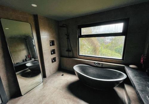 ein Badezimmer mit einer großen Badewanne und einem großen Spiegel in der Unterkunft SURFLAB VILLA in Balian