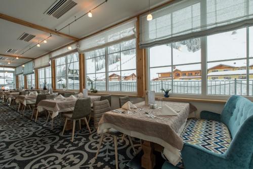 een restaurant met tafels, stoelen en ramen bij Hotel Sportalmmm, Hoch-Genuss in Zauchensee