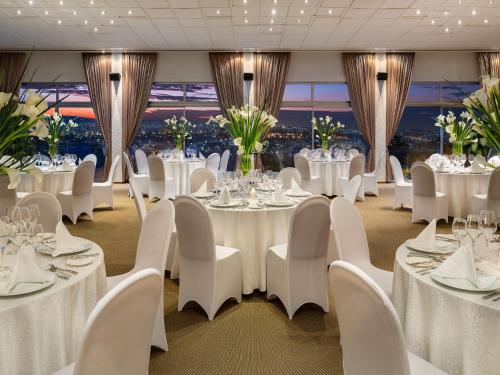 a banquet room with white tables and white chairs at Hotel des Mille Collines in Kigali