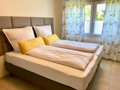 a bed with yellow and white pillows and a window at RIVERBLICK NEAR FRANKFURT in Hainburg