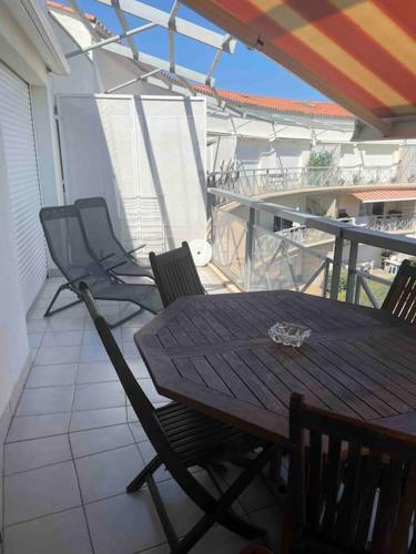 une table et des chaises en bois sur un balcon dans l'établissement Frontignan: appartement en front de mer avec vue, à Frontignan