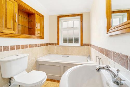 a bathroom with a tub and a toilet and a sink at The Paddocks Romantic Retreat in Boston