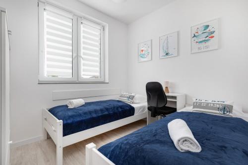 a bedroom with two beds and a desk and window at Apartament Bursztynowa Przystań in Dziwnówek