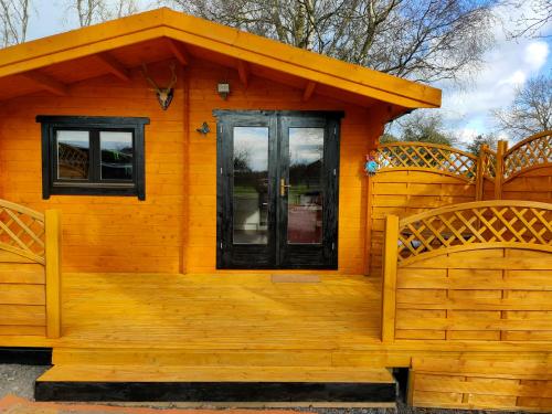 ein kleines orangefarbenes Haus mit einer Veranda und einer Tür in der Unterkunft ANNES LOG CABIN in Nobber
