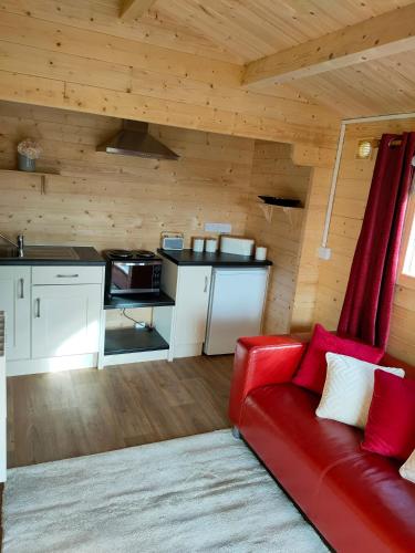 a living room with a red couch and a kitchen at ANNES LOG CABIN in Nobber