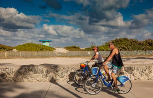 two men riding bikes on a sidewalk near the beach at The Tony Hotel South Beach in Miami Beach
