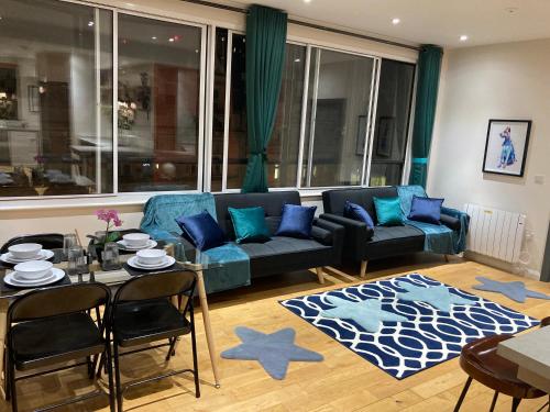 ein Wohnzimmer mit einem blauen Sofa und einem Tisch in der Unterkunft Central Sheffield 3BED 3BATH IV Pent-Apartment in Sheffield