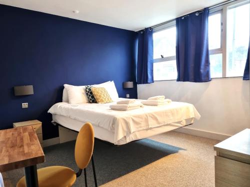 a bedroom with blue walls and a bed with chairs at Heritage House Apartments in Swindon