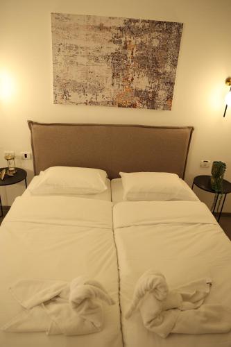 a bedroom with two beds with white sheets and towels at חדרי בוטיק B.Y in Bet Sheʼan
