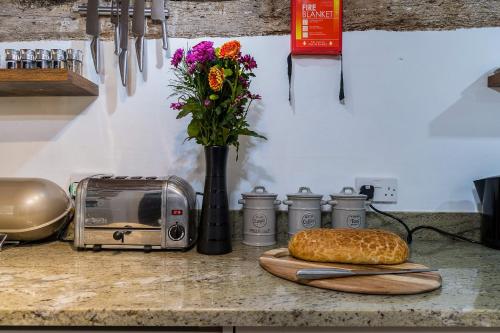 a counter top with a toaster and a loaf of bread at Lantau Cottage: Historic Elizabethan house very close to the beach in Looe