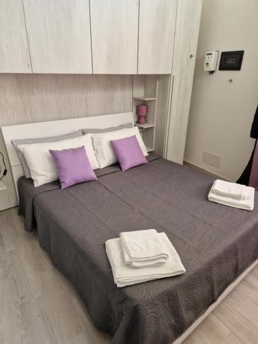 a bedroom with a large bed with purple and white pillows at LA CASETTA in Cagliari