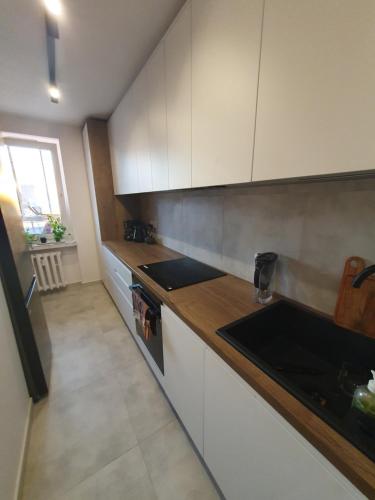 cocina con armarios blancos y encimera en Apartamenty Cześć Kraków en Cracovia