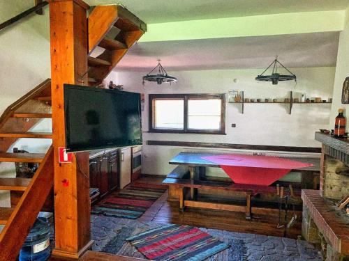 ein Wohnzimmer mit einem Tisch, einem TV und einer Treppe in der Unterkunft Къща за гости Диляна 
