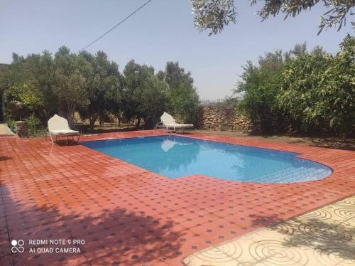 einen Pool mit zwei Stühlen auf einem Ziegelboden in der Unterkunft Villa avec piscine in Essaouira