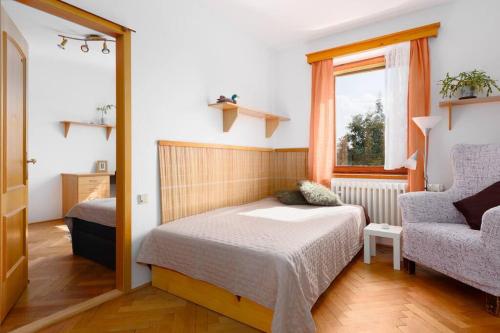 a bedroom with a bed and a chair and a window at Entire house with garden near Prague in Benešov