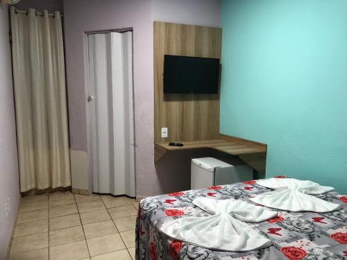 a bedroom with a bed and a television in it at Pousada Moryah in Paripueira