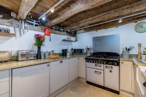 una cucina con mobili bianchi e un forno a piano cottura di Lantau Cottage: Historic Elizabethan house very close to the beach a Looe