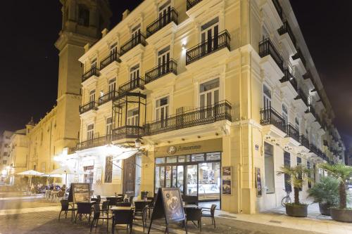 un bâtiment jaune avec des tables et des chaises devant lui dans l'établissement Hotel San Lorenzo Boutique, à Valence