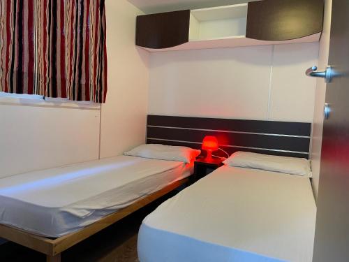2 łóżka w małym pokoju z czerwonym światłem w obiekcie Villaggio Camping Europa w mieście Sottomarina