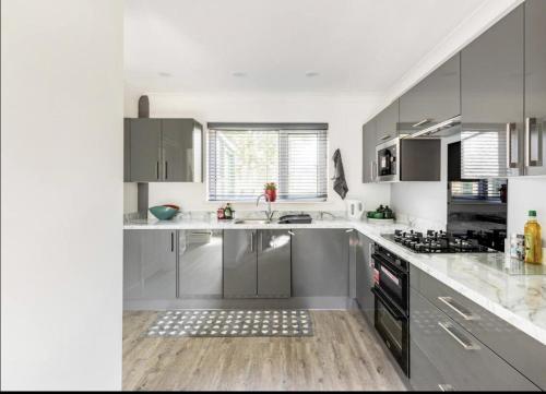 a kitchen with stainless steel appliances and white cabinets at Come & unwind in Charming 5 Bed House in Blackburn in Blackburn