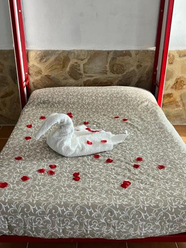 un cisne blanco de peluche sobre una cama con rosas en La casita de los sueños, en Casarrubios del Monte