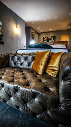a leather couch with pillows on it in front of a bed at Drì bed & breakfast in Rocca di Papa