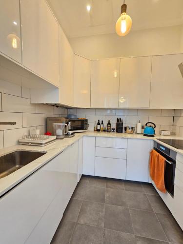 een witte keuken met witte kasten en een wastafel bij 1 bed flat near Little Venice and Paddington in Londen