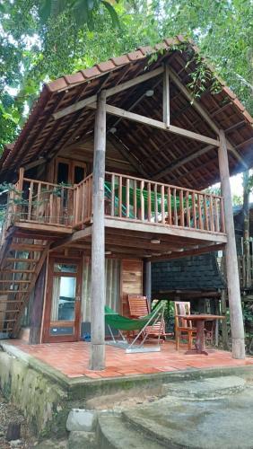 a large wooden house with a deck and a table at Green Bamboo Lodge Resort in Cat Tien