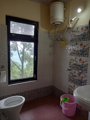 a bathroom with a sink and a toilet and a window at Cardamom Blues in Aritar